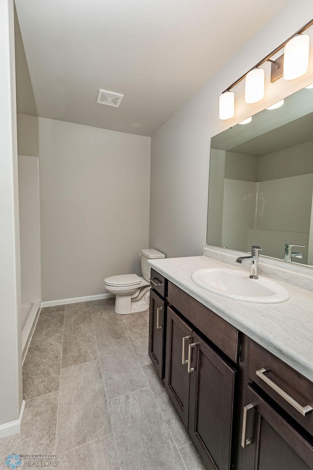 bathroom featuring toilet, vanity, and a shower