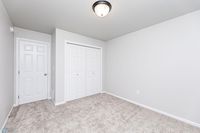 unfurnished bedroom with light carpet and a closet