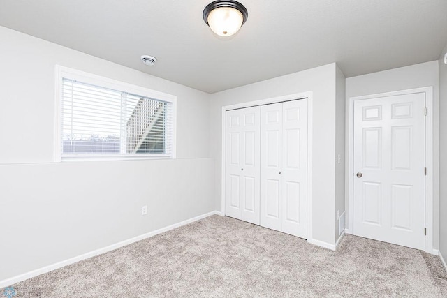 unfurnished bedroom featuring light colored carpet and a closet