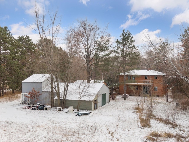 snow covered back of property with an outbuilding and a garage