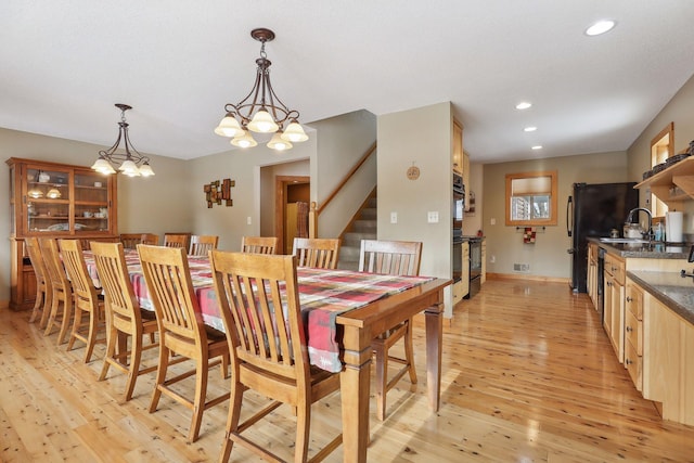 dining room featuring light hardwood / wood-style flooring, an inviting chandelier, and sink