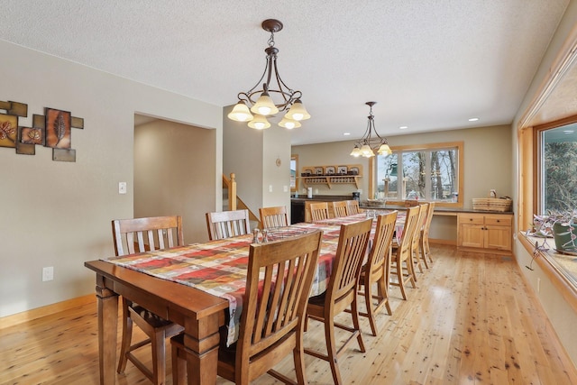 dining space featuring a textured ceiling, light hardwood / wood-style flooring, and an inviting chandelier