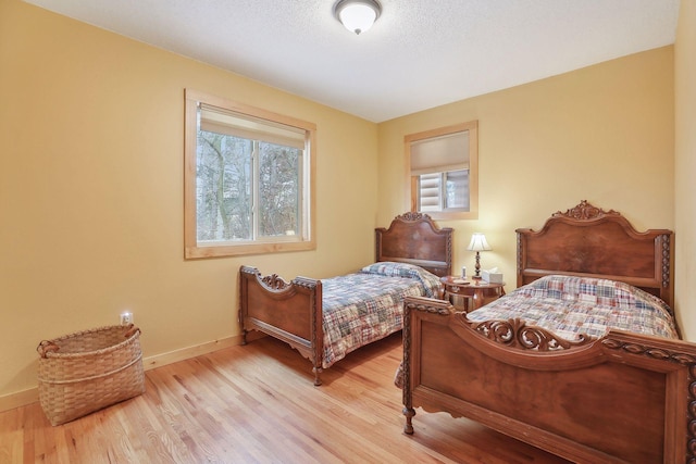 bedroom with a textured ceiling and light hardwood / wood-style flooring