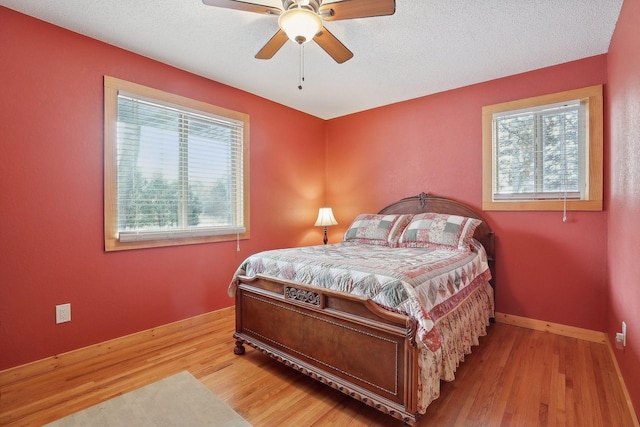 bedroom with ceiling fan, light hardwood / wood-style floors, and a textured ceiling