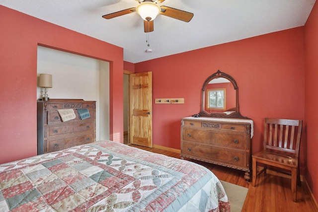 bedroom featuring ceiling fan, hardwood / wood-style floors, and a textured ceiling