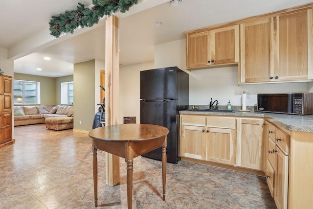 kitchen featuring light brown cabinetry, sink, and black appliances