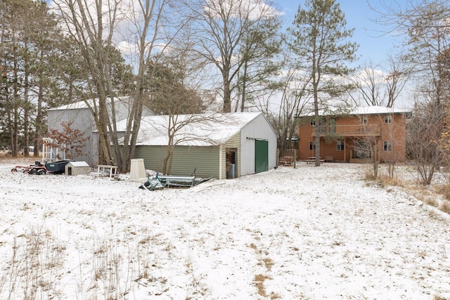 snow covered rear of property featuring a garage and an outdoor structure