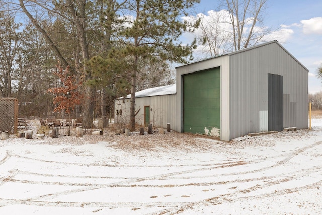 snow covered structure featuring a garage