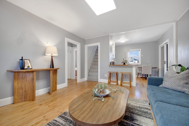 living room with light wood-type flooring, baseboards, and stairs