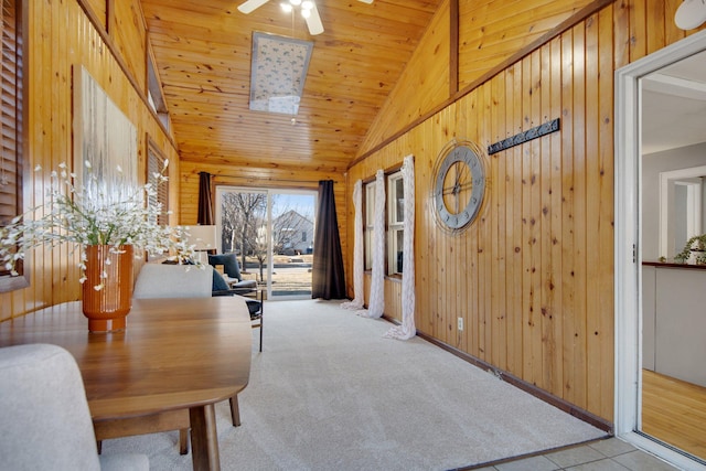 carpeted dining room featuring a ceiling fan, wood ceiling, wood walls, and high vaulted ceiling