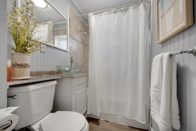 bathroom featuring shower / bathtub combination with curtain, vanity, toilet, and wood finished floors