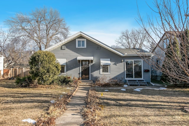 bungalow featuring entry steps, fence, and a front lawn