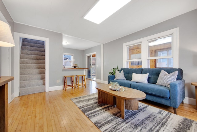 living room featuring hardwood / wood-style floors, baseboards, and stairway