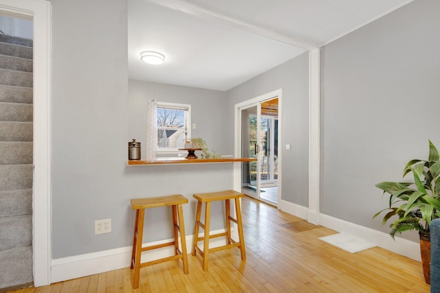 dining area with light wood-type flooring, baseboards, and stairway