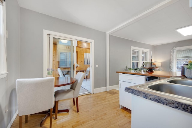kitchen with light wood finished floors, white cabinets, and baseboards