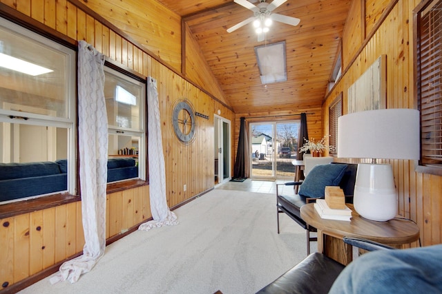 living area featuring wooden walls, lofted ceiling, a ceiling fan, wooden ceiling, and carpet floors