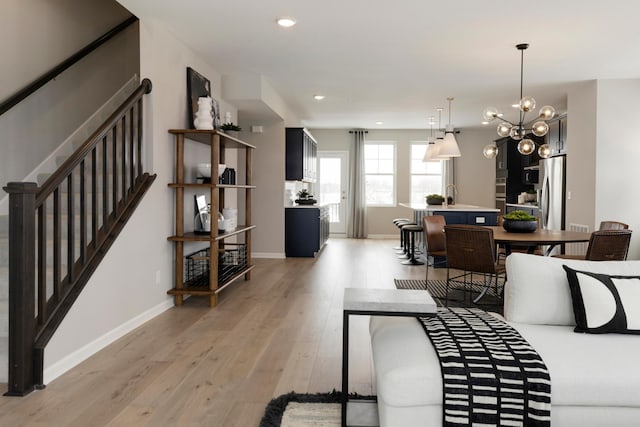 living room with a notable chandelier, light wood-type flooring, and sink