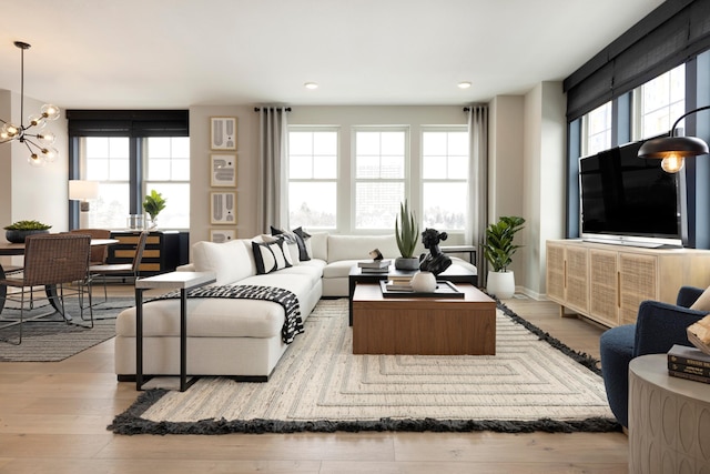 living room with a wealth of natural light, light hardwood / wood-style floors, and an inviting chandelier