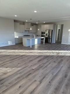 kitchen featuring stainless steel fridge with ice dispenser, light hardwood / wood-style flooring, and a kitchen island with sink