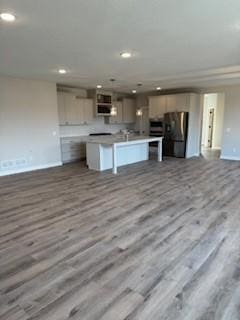 kitchen featuring a center island with sink, stainless steel refrigerator, and light hardwood / wood-style flooring