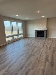 unfurnished living room with hardwood / wood-style flooring and a stone fireplace