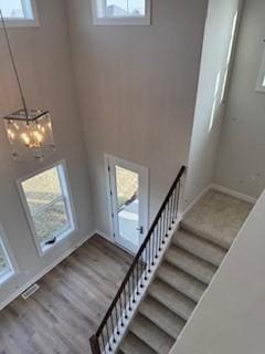 stairway featuring wood-type flooring and an inviting chandelier