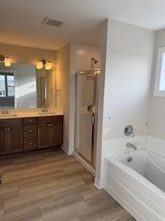 bathroom with hardwood / wood-style flooring, vanity, and plus walk in shower