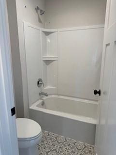 bathroom with washtub / shower combination, tile patterned floors, and toilet