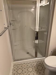 bathroom with toilet and a shower with shower door