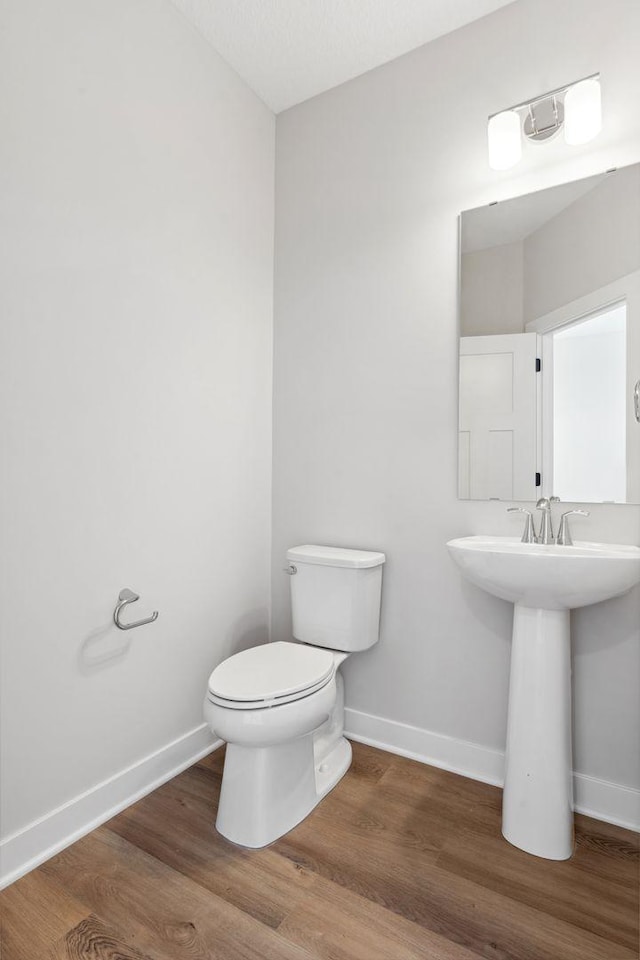 bathroom with wood-type flooring, toilet, and sink