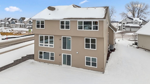 snow covered back of property featuring central AC unit