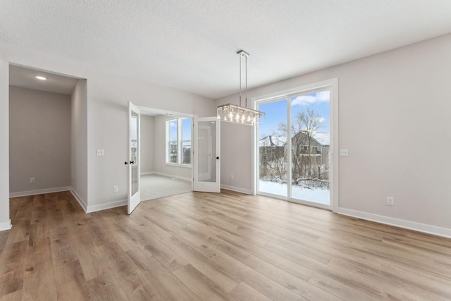 unfurnished dining area with light hardwood / wood-style flooring and a textured ceiling