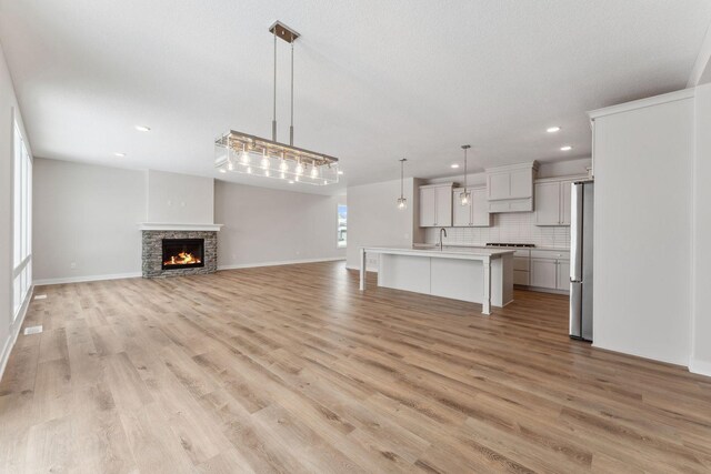 unfurnished living room with a fireplace, sink, and light hardwood / wood-style flooring