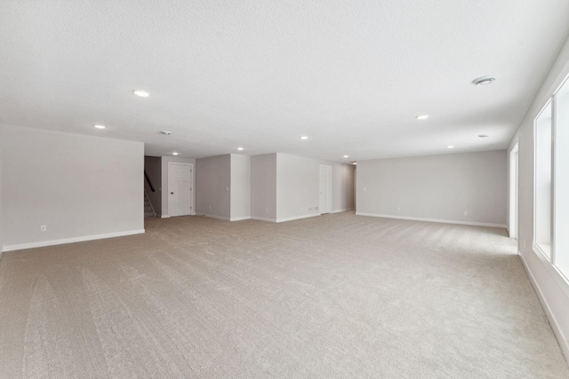 unfurnished room with light colored carpet and a textured ceiling