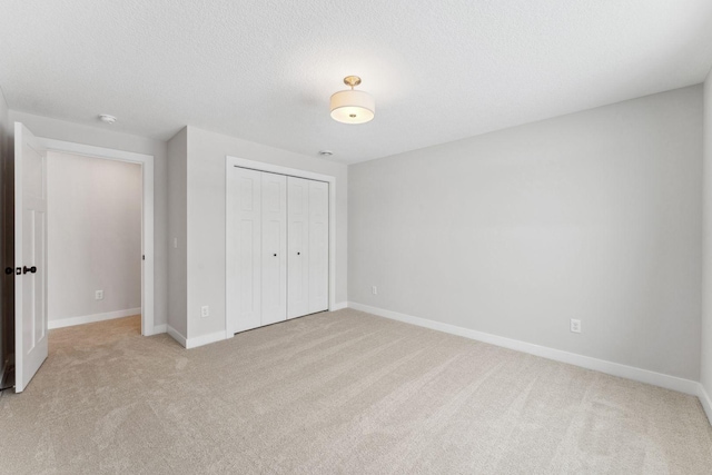 unfurnished bedroom featuring light colored carpet, a textured ceiling, and a closet