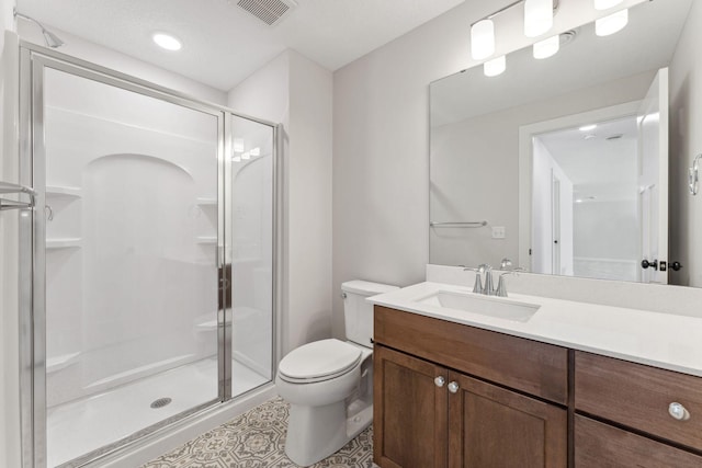 bathroom featuring a shower with door, vanity, and toilet