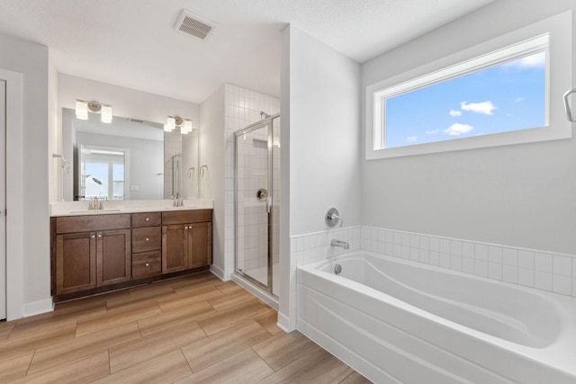 bathroom featuring vanity, separate shower and tub, and a textured ceiling