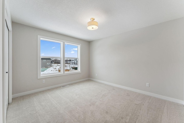 unfurnished bedroom with a closet, light carpet, and a textured ceiling