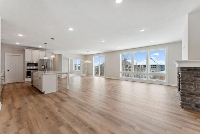 unfurnished living room with light hardwood / wood-style flooring and a textured ceiling