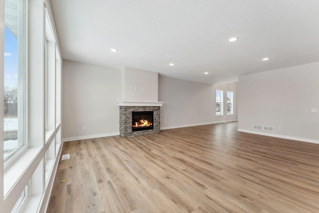 unfurnished living room featuring a fireplace and light hardwood / wood-style floors