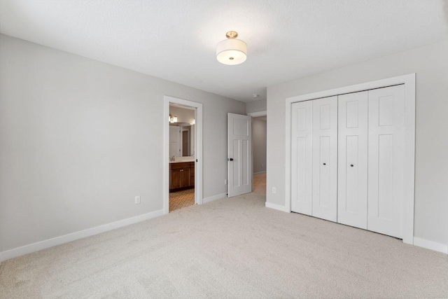 unfurnished bedroom with connected bathroom, light colored carpet, and a closet