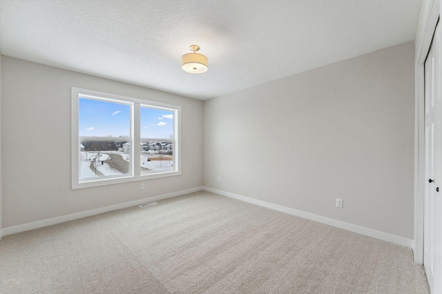 unfurnished room featuring light carpet and a textured ceiling