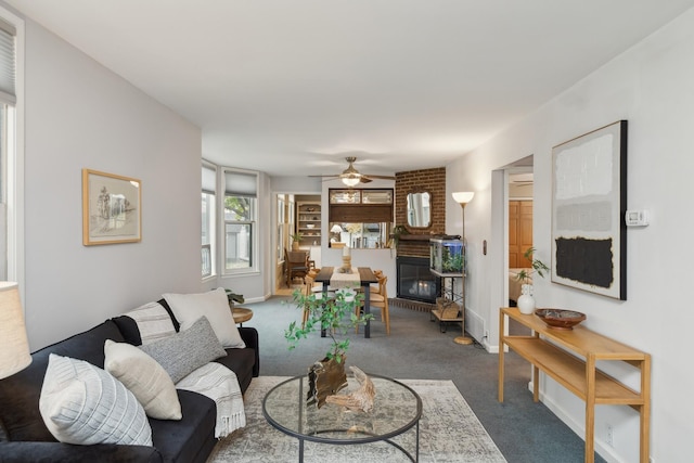 living room featuring ceiling fan, dark carpet, and a fireplace