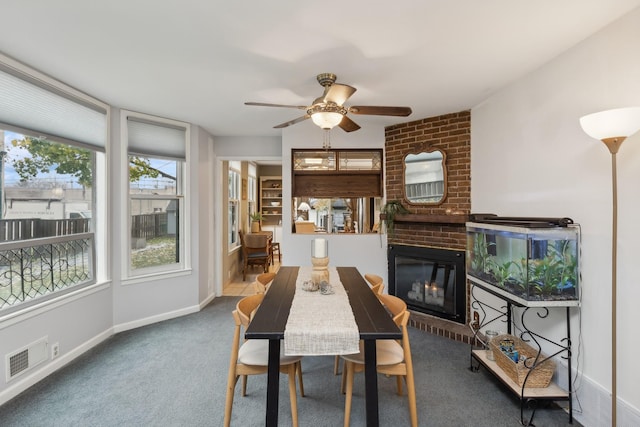 carpeted dining room with ceiling fan and a fireplace