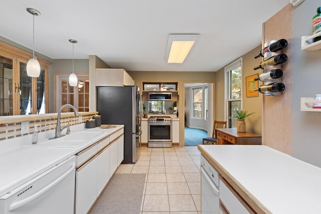 kitchen featuring white cabinets, appliances with stainless steel finishes, sink, hanging light fixtures, and light tile patterned flooring