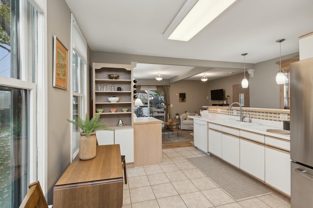 kitchen featuring white cabinetry, stainless steel fridge, white dishwasher, pendant lighting, and sink