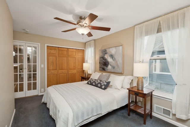 bedroom with french doors, ceiling fan, dark carpet, and multiple windows