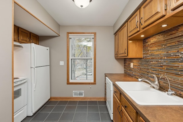 kitchen featuring sink, dark tile patterned flooring, backsplash, and white appliances