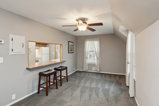 interior space with white fridge, a kitchen bar, kitchen peninsula, dark colored carpet, and lofted ceiling