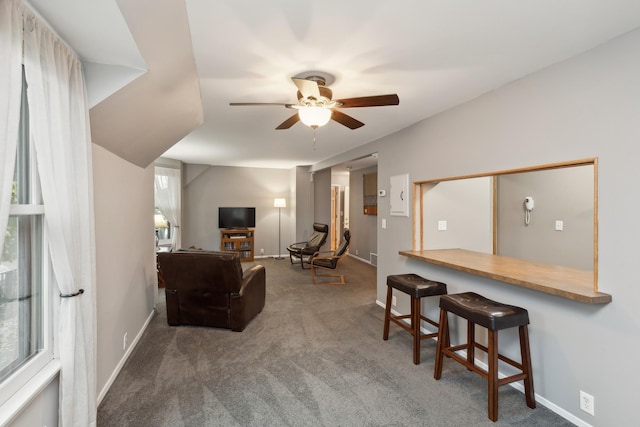 living room featuring ceiling fan and dark carpet